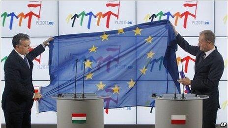 Hungary PM Viktor Orban, left, hands EU flag to Poland's PM Donald Tusk, 1 July 11