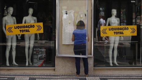 A woman arranges a display outside a department store before the sales season in Lisbon