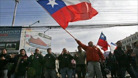 A worker from Chile's state-owned copper mining company Codelco, waves a Chilean flag next to co-workers during a strike in Los Andes, Chile, 11 July 2011.