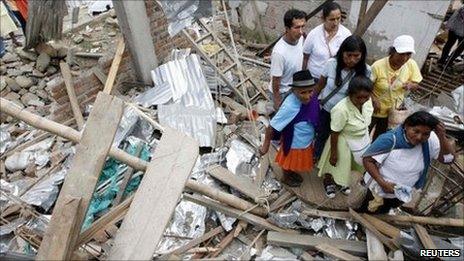 A family looks at their house that was damaged after being hit by a blast in Toribio, in Cauca province, 9 July, 2011.