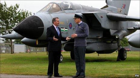 Defence Secretary Liam Fox speaks with Station Commander Group Captain Andy Hine in front of a Tornado GR4 at RAF Lossiemouth