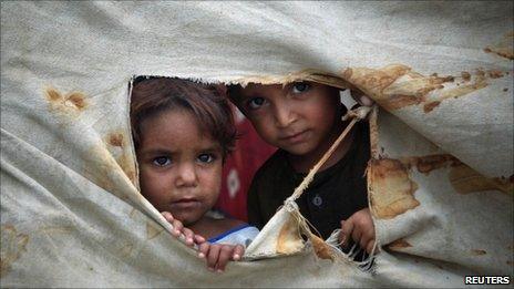 Internally displaced children peep through a tent used by their family at a camp for flood victims in Sir Darriyya, Charsadda, northwest Pakistan July 28, 2011.