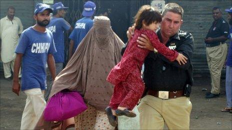 A policeman evacuates a Pashtun family from a troubled area of Karachi (01 Aug 2011)