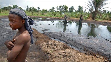 Boy stands near an abandoned oil well head leaking crude oil, 11 April 2007, in Kegbara Dere, Ogoni Territory