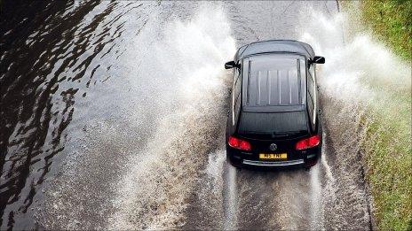 A car driving through a flooded section of the A1058 Coast Road to Tynemouth