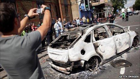 Man taking digital photo of burned out car