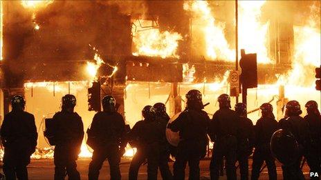 Officers in riot gear near burning shops in Tottenham on Sunday