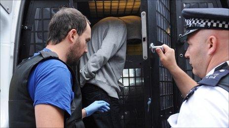 A young male suspect is led to a secure police vehicle after being arrested