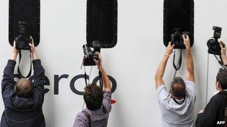 Press photographers take pictures of rioters being driven away in a prison van