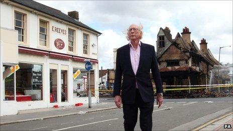 Maurice Reeves stands near the destroyed shop and the smaller premises