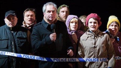 A crowd of people near police tape - London Road production photo by Helen Warner