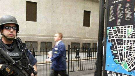 A policeman stands guard on Wall Street with a worker passing by