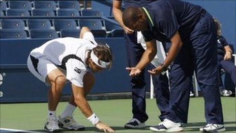 David Ferrer examines the spot where water is seeping on to the court