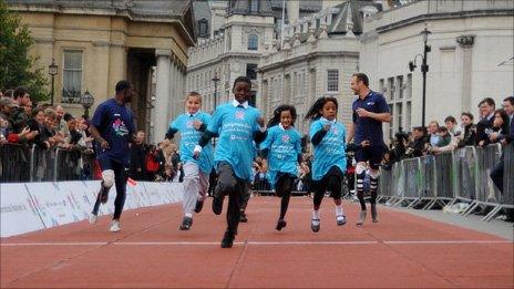 Oscar Pistorius (r) and Jerome Singleton (l) race with children in Trafalgar Square