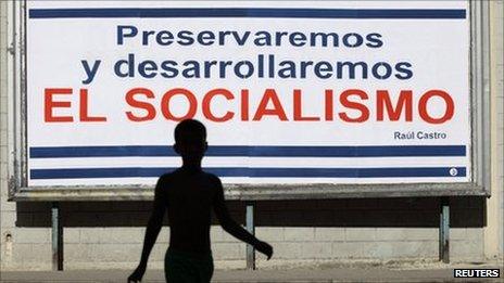 Boy crosses a street near a billboard in Havana, saying "we will preserve and develop socialism" on 3 August, 2011.