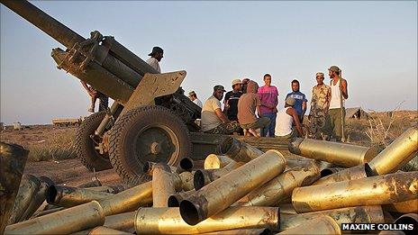 Anti-Gaddafi forces stand next to used artillery munitions