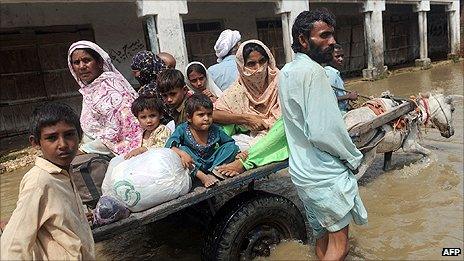 A Pakistani family ride on a donkey-cart through flood waters