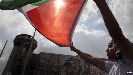 A man waves a Palestinian flag near an Israeli army watchtower at a checkpoint between Jerusalem and Ramallah on 23 September 2011