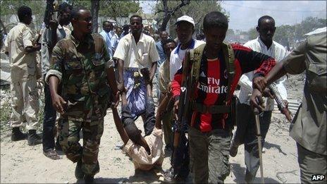 Somalia government soldiers carry an injured man from the scene of a suicide attack in Mogadishu on Tuesday