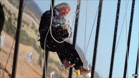 Richard Branson opens a bottle of champagne while abseiling down the side of Spaceport America on 17 October 2011