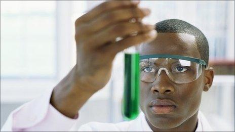 Young man holding a test tube with green liquid