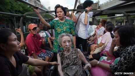 Bangkok residents sit in a truck as they drive away from a flooded area of the capital on 26 October 2011