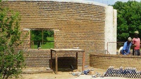 People building a wall made from plastic bottle packed with sand the Nigieran village of Yelwa