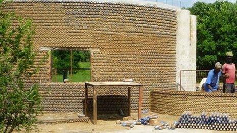 People building a wall made from plastic bottle packed with sand the Nigieran village of Yelwa