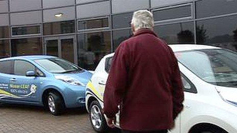 Man next to two Nissan leaf electric cars