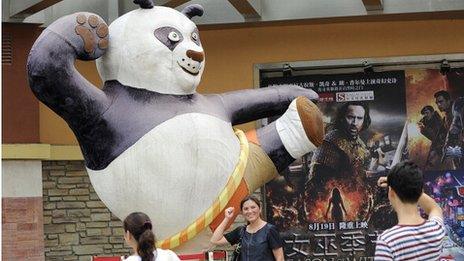 People pose for photos by movie advertising outside a cinema in Beijing