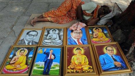 A woman on the pavement selling posters of Ambedkar and the Buddha