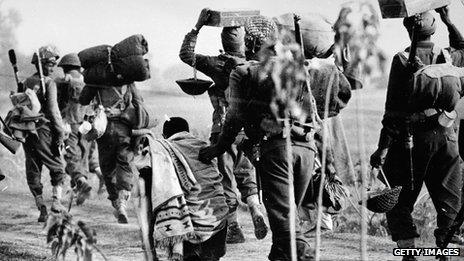 An elderly refugee walks alongside Indian troops advancing into the East Pakistan (Bangladesh) area during the Indo-Pakistani war of 1971