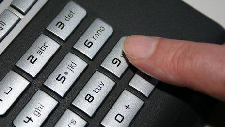 Person dialling 9 on a telephone