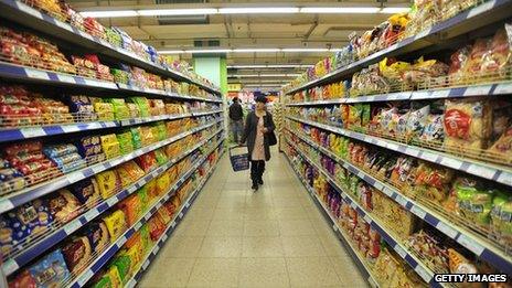 A shopper walks down an aisle in the supermarket