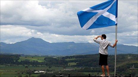 A man holds Scotland's flag aloft as he looks out over the Carse of Stirling