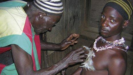 Juju practitioner administering a charm to a young man