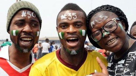 People with their faces painted with the national green and white colours, and different naira denominations on their forehead, pose during a Lagos demonstration