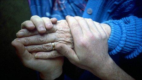 Carer holding elderly woman's hand