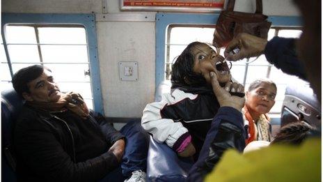 Health workers administer polio drops to children on a train near Ghaziabad, on the outskirts of Delhi, Jan 2012