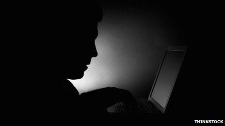 A silhouette of a man using a laptop