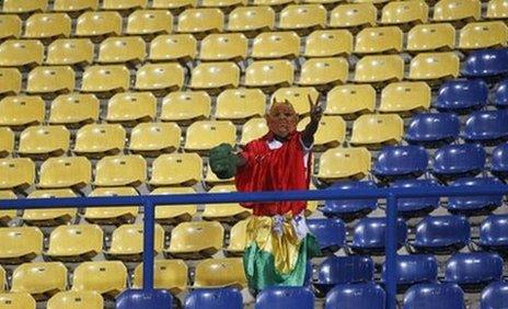 A Guinea fan stands among rows of empty seats