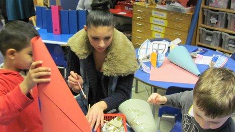 Teenager helps toddlers make paper hats