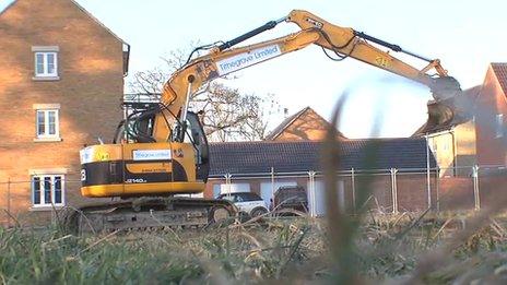 A mechanical digger begins to work on a building site