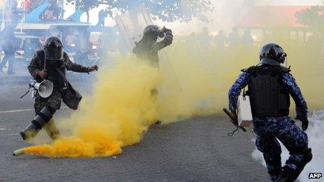 Maldivian policemen try to take cover as anti-government demonstrators throw back a teargas canister in the capital island Male on February 8, 2012