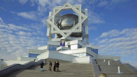 Women walk down steps beneath a portrait of President Gurbanguly Berdimuhamedow in Ashgabat on 7 February 2012