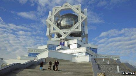 Women walk down steps beneath a portrait of President Gurbanguly Berdimuhamedow in Ashgabat on 7 February 2012