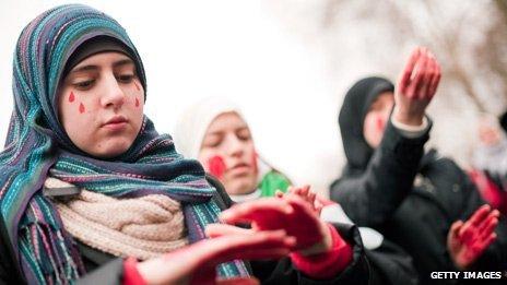 Protesters apply red paint to their hands outside the Syrian embassy in London
