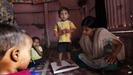 A volunteer weighs a malnourished child at the Apanalay center in Mumbai, India (Jan 11, 2012)