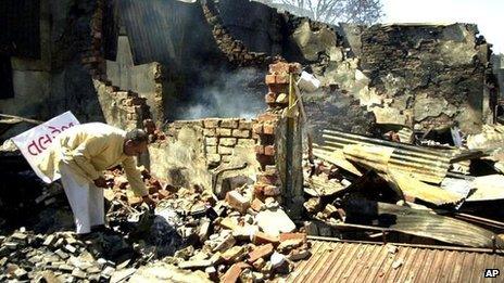 A businessman sorts through the remains of his burned shop in Ahmedabad, India - 4 March 2002