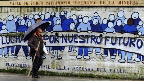 A man walks past a graffiti which reads "Fight for our future" in Turon, northern Spain